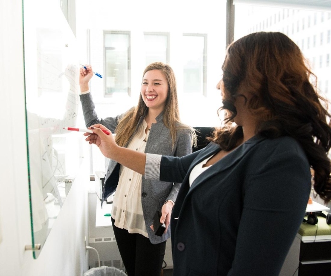 two women in a corporate setting drawing up a project plan